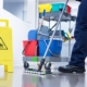 Front view of a custodian mopping the floor with a wet floor sign in the frame