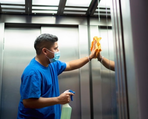 Janitor disinfecting high touch surface of elevator