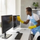 Professional janitor cleaning office desk and computer