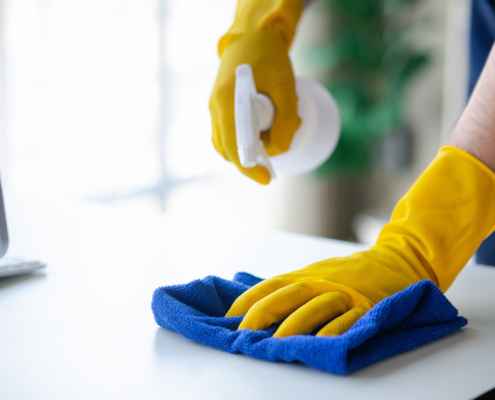 Side view, cleaning staff is using cloth and spraying disinfectant to wipe the glass in the company office room