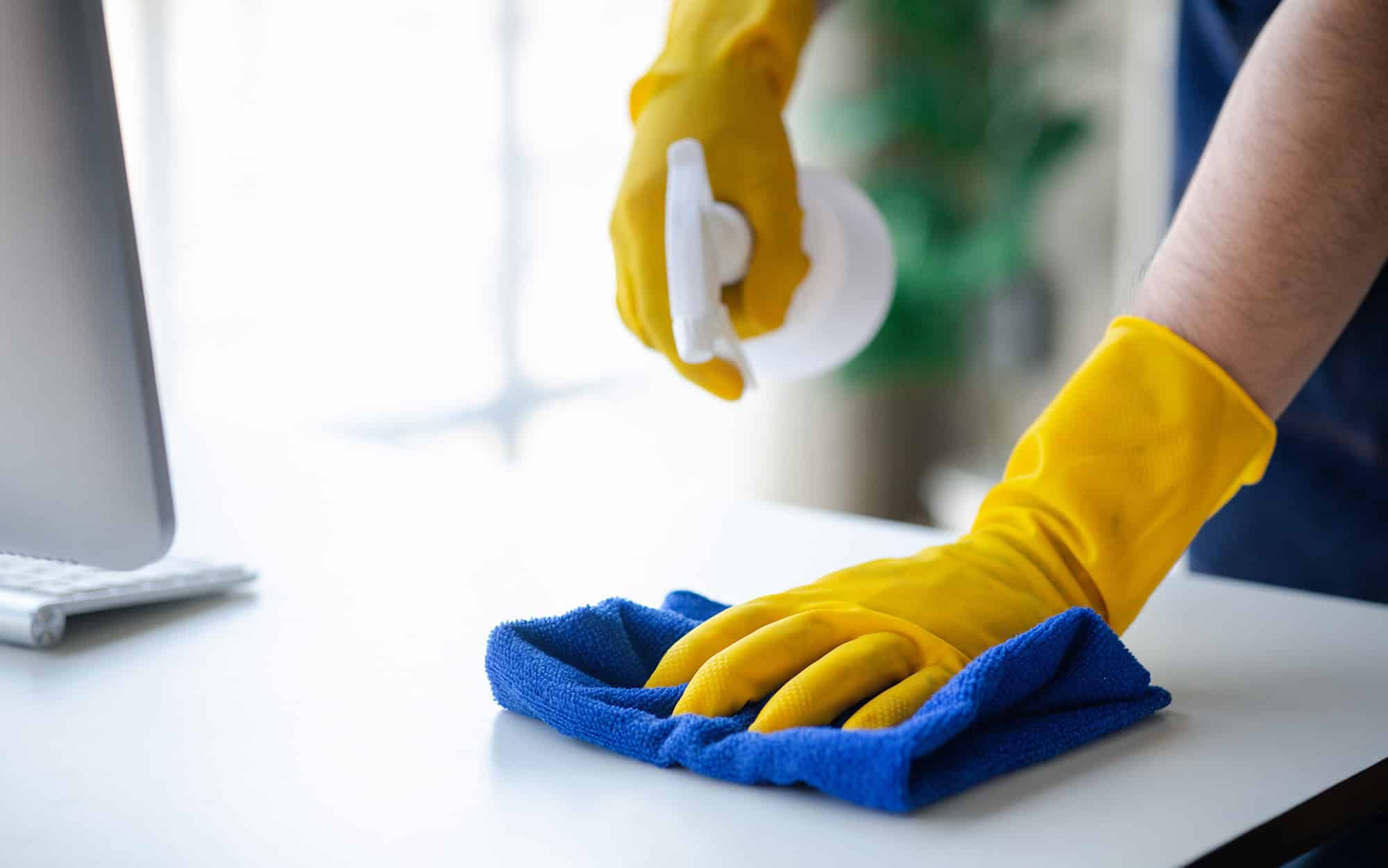 Side view, cleaning staff is using cloth and spraying disinfectant to wipe the glass in the company office room