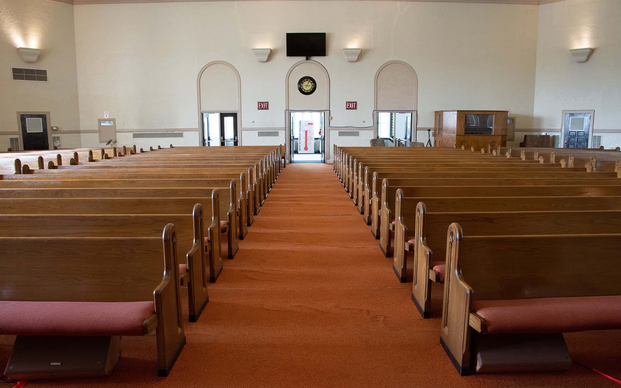 wide angle shot of interior of empty church lit by faint sunlight